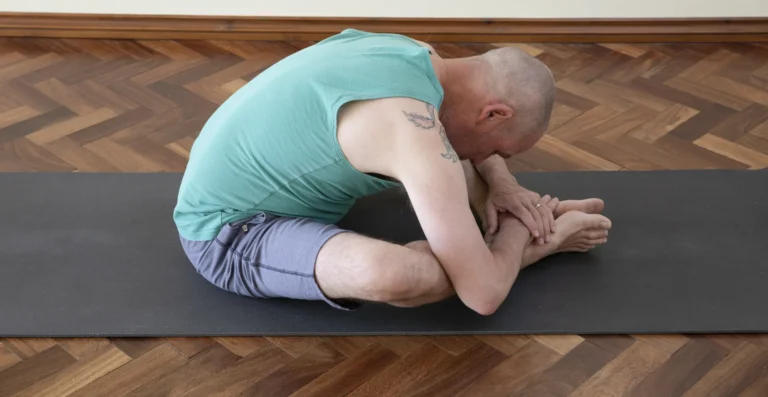 Norman Blair folded forward in butterfly pose on a mat