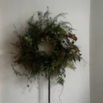 A wreath of foraged greenery hanging on a white wall