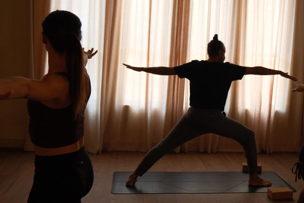 Yoga class in the mat room - an instructor silhouetted against sheer large curtains